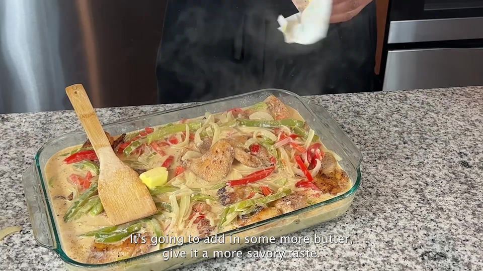 Glass baking dish of fried wings smothered in creamy pepper-and-onion gravy with a pat of butter on top, steam rising as more butter is added.